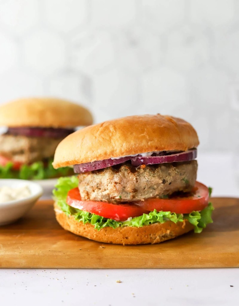The image showcases a juicy turkey burger with lettuce and tomato
