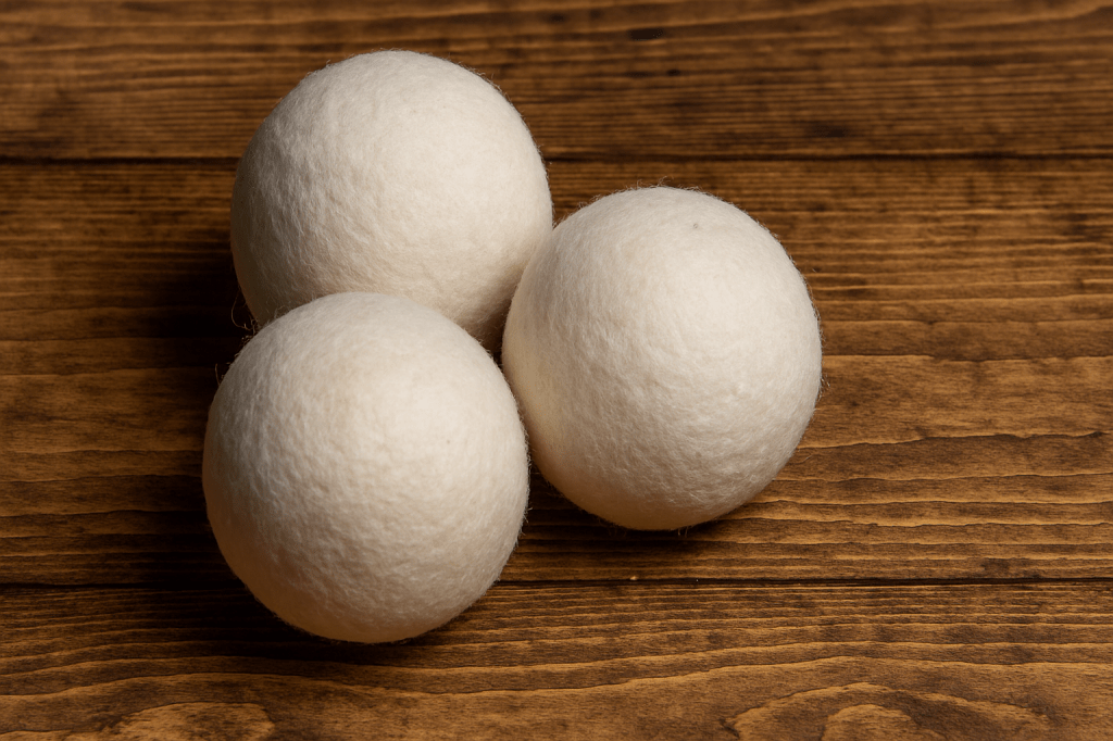 Three wool dryer balls on a natural wood background with drop shadow